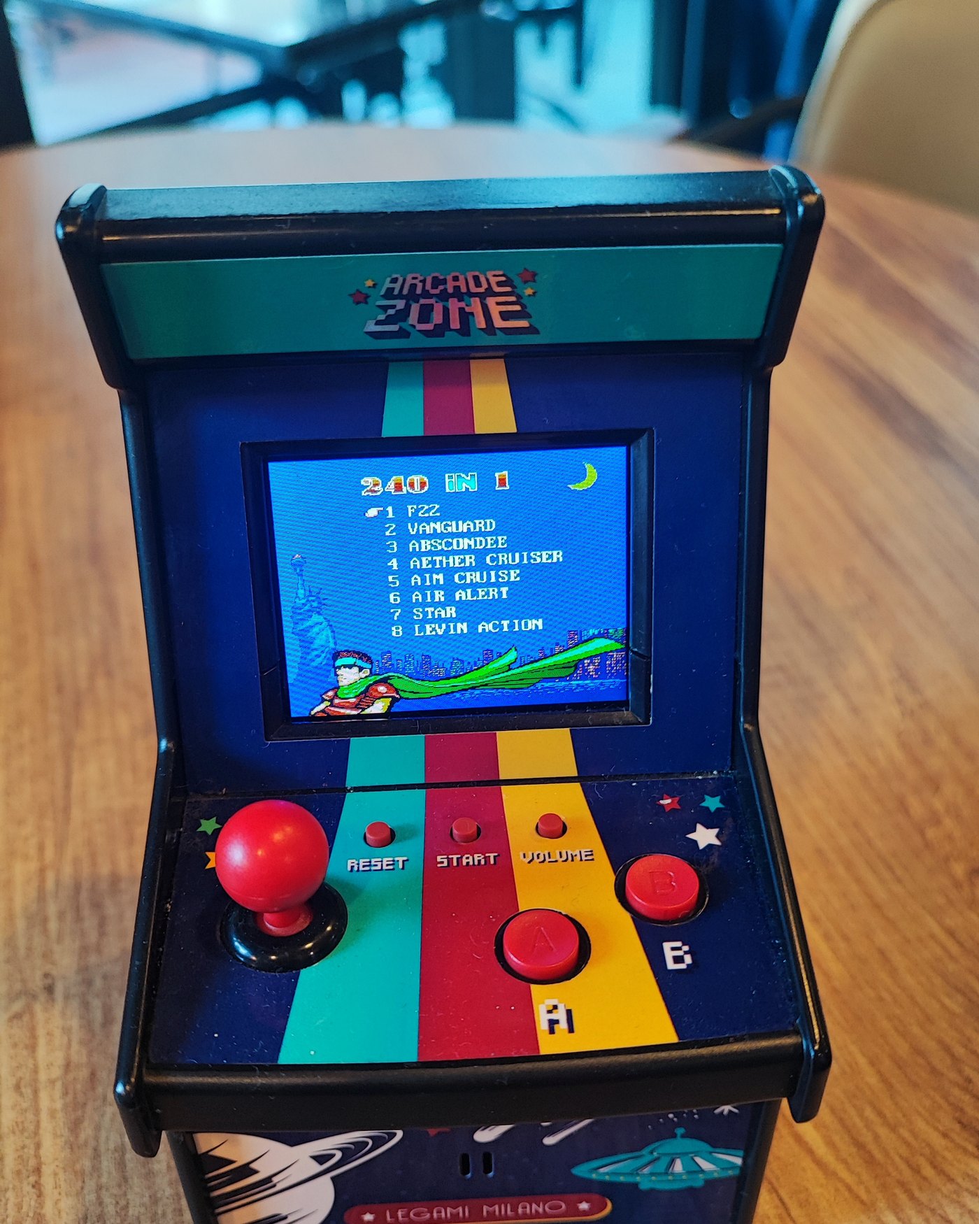 Kafedeki mini arcade konsolu — masaya kurulan, joystickli küçük oyun makinesi